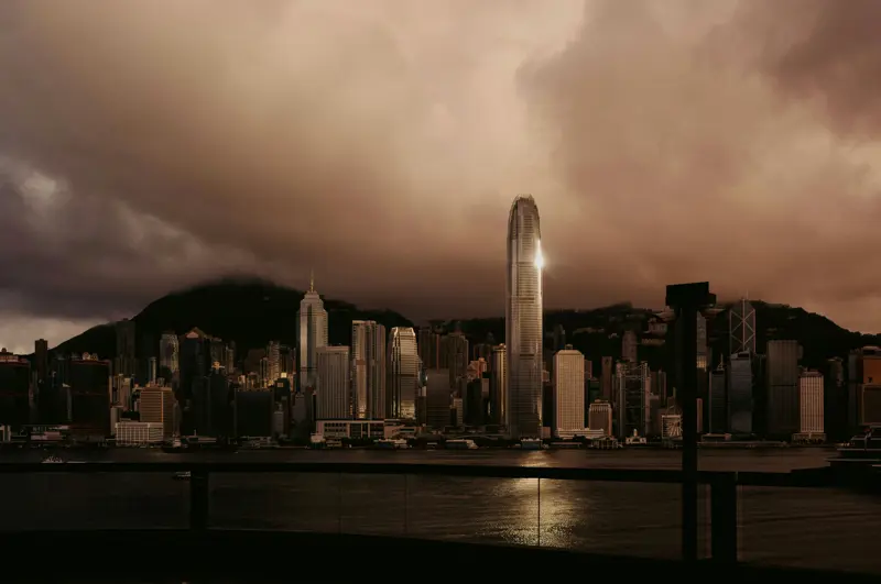 Hong Kong skyline with tall skyscrapers reflected over Victoria Harbour at dusk