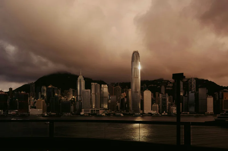 Hong Kong skyline with tall skyscrapers reflected over Victoria Harbour at dusk